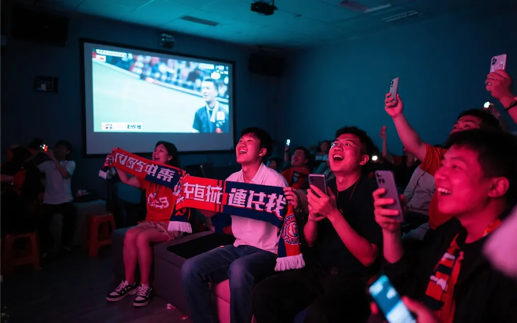 中国球迷在室内线下观赛活动中举起围巾与手机拍摄，屏幕显示比赛直播的氛围